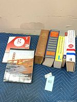 All seven books grouped on blanket, showing spines and size comparison