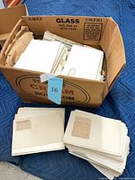 Full box and stacks of cardstock boards with mounted newspaper clippings