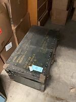 Full view of olive drab riveted trunk with stenciled markings