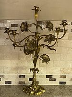 Front view showing seven candle cups, floral motif, ornate base