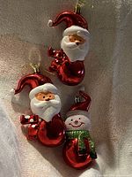 Front view of three glass ornaments: two Santas, one snowman