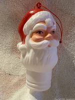 Front view of molded vinyl Santa head ornament with hanging cord