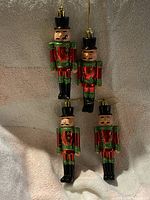 Front view of four nutcracker ornaments showing coloring and hanging cords