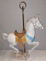 Left side view of white resin carousel horse, brass pole, cloud base