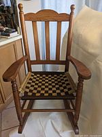 Front view of child-sized wooden rocking chair showing woven checkerboard seat and overall design