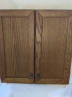 Front view of closed oak cabinet dartboard