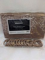 Front view of packaged gold embroidered fabric shower curtain with hooks