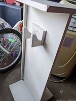 Angled view of white wood skateboard stand showing board bracket and base