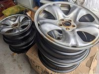 Stack of four silver alloy rims showing side profiles and rust