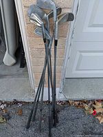 Eight golf irons leaning against brick wall and garage door
