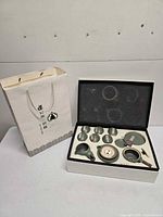 Gift bag, closed box and open presentation box displaying full tea set layout