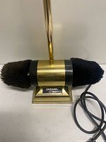 Front view showing brass-tone base, black housing, dual brushes, Dremel label