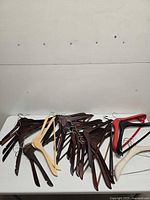 pile of dark and light wooden hangers with a few plastic hangers on tabletop