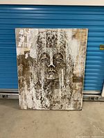 Front view shows full artwork with abstract face