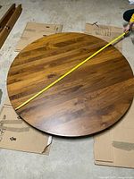 Top view of round tabletop with tape showing 64 inch diameter