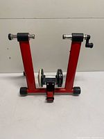 Full front view of red steel folding trainer frame with roller and resistance unit