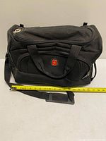 Front view of SwissGear black duffel with measuring tape showing length