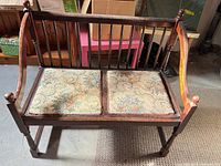 Front view of wooden spindle-back bench with tapestry cushions