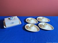 Group shot of butter dish and four egg cups on blue cloth
