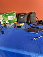 Overview of three digital cameras, two cases, Fujifilm box