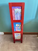 Front view of red wood CD cabinet with three art inserts