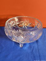 Side view of clear cut crystal bowl showing pinwheel and geometric cuts, on one of its feet