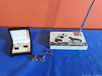Overview of cufflinks in box, oval cufflinks, tie clip and carved stone pen set