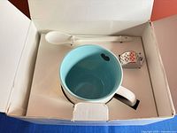 Open box showing mug, spoon and infuser arranged in original packaging