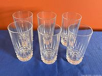 Front angled view of six clear highball glasses displaying cut pattern and faceted bases