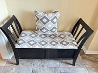 Front view of black wooden hall bench with patterned cushion and pillow