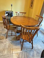 wooden oval dining table with four of six chairs shown