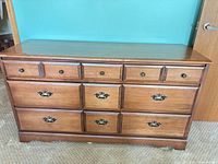Front view of wooden lowboy dresser showing drawers and hardware
