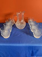 Pitcher centered with eight matching tumblers displayed symmetrically