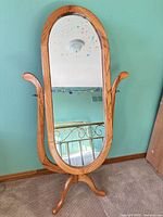 Front view of oak-finish oval swivel mirror on tripod base