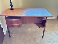 Front view of teak desk showing drawers and shelf