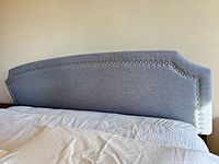Front view of light blue upholstered headboard on bed