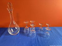 Decanter with stopper and six goblets on blue surface