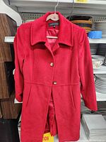 Front view of red Anne Klein coat on hanger showing color, collar, button front