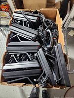 Box containing stacked Avaya desk phones showing handsets, stands, cords