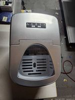 Top and front view of silver Cook's Essentials countertop ice maker with viewing window