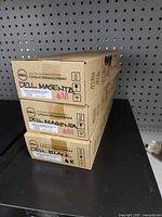 Three sealed Dell toner cartridge boxes stacked, labels visible showing Magenta and Black versions