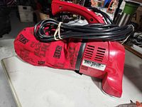 Left side view of red Dirt Devil Plus hand vacuum showing cloth bag and cord