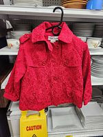 Front view of red jacquard coat on hanger