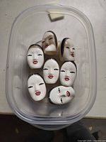 Top view of all seven bone china Noh face napkin rings in container