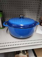 Full view of blue enameled Dutch oven with lid on shelf