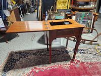 Cabinet open showing sewing machine cut-out and hinged leaf