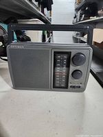 Front view showing speaker grille, tuning scale, knobs, handle