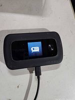 Front view of powered-on Orbic Speed hotspot connected to cable