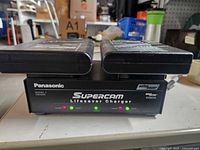 Front view of charger with two batteries docked, showing model and indicator lights