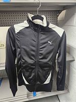 Front view of black and white Puma track jacket on hanger